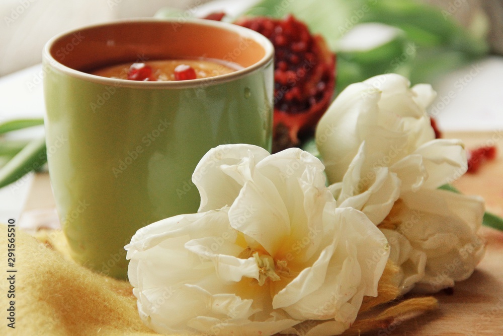Tender white flower and cup of tea with pomegranate