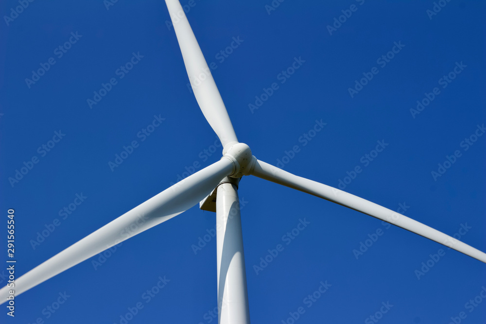 Close up view of a giant wind power electric turbine with blue sky background Close up view of a giant wind power electric turbine with blue sky background