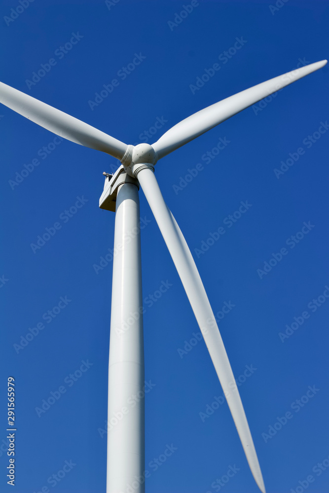 Close up view of a giant wind power electric turbine with blue sky background