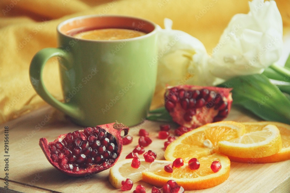 Tender white flower and cup of tea with pomegranate