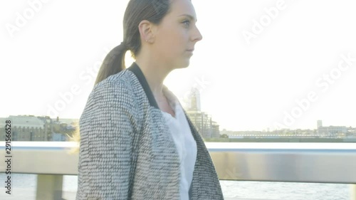 Steady cam view of an attractive caucasian business woman commuter walking on London bridge at sunset