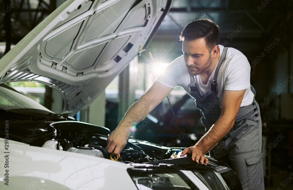 Young auto mechanic examining car oil in a repair shop Young auto mechanic examining car oil in a repair shop