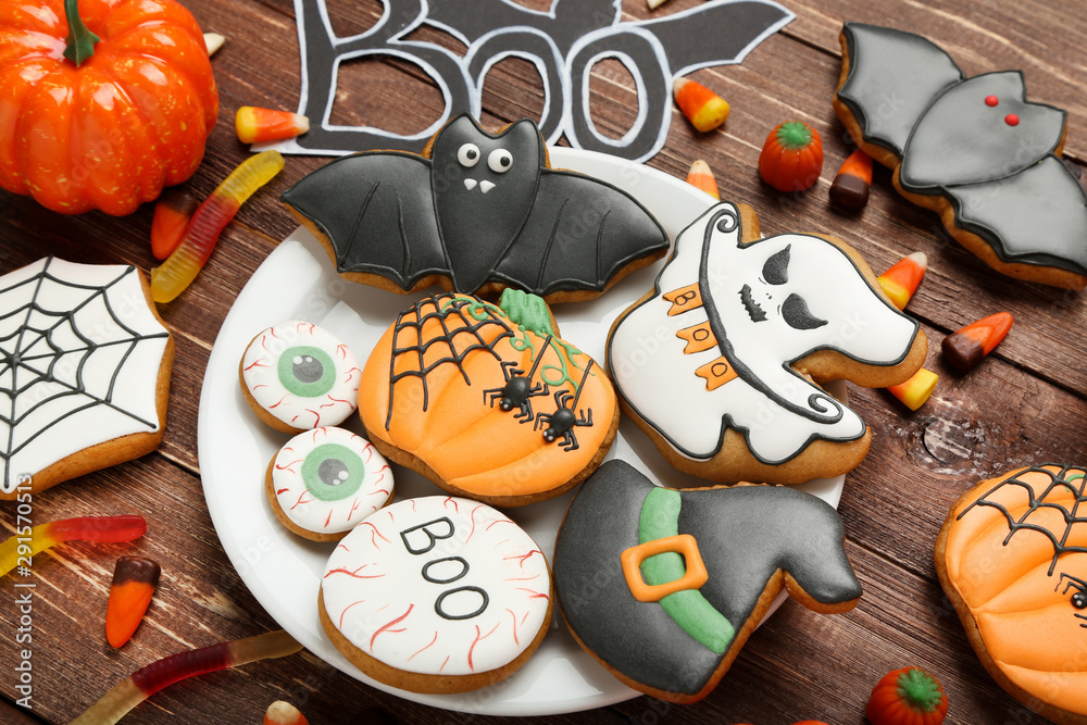 Halloween gingerbread cookies with candies in plate on brown wooden table