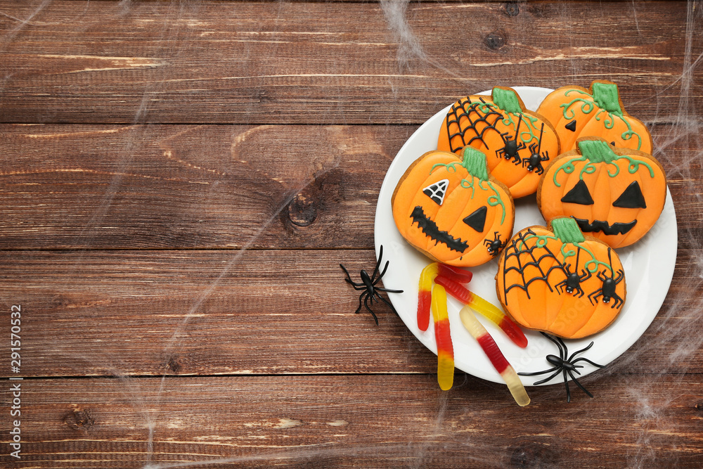 Halloween gingerbread cookies with spiders in plate on brown wooden table