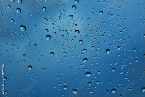 Rain drops with selective focus on transparent glass. Glass surface with water drops, blue toned. Window with raindrops. water drops on glass