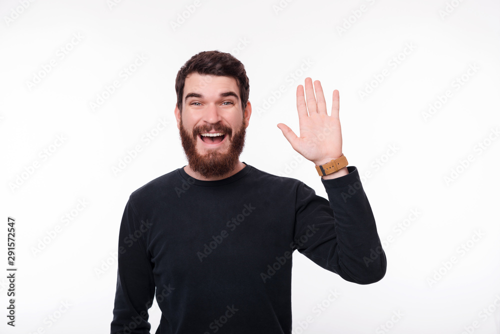 Portrait of cheerful handsome young man making Hello gesture