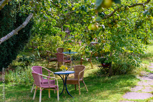 Cozy sitting areas made of wicker chairs and tables in a romantic orchard (format landscape).