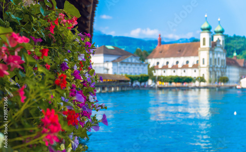 Lucerne / Switzerland. Colorful flowers at the Chapel Bridge (Kapellbrücke) with the Jesuit Church in the distance