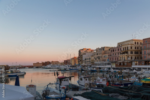 Small picturesque city port at sunset. Anzio, Lazio region, Italy. Fishing boats, small yachts on beautiful evening sky background