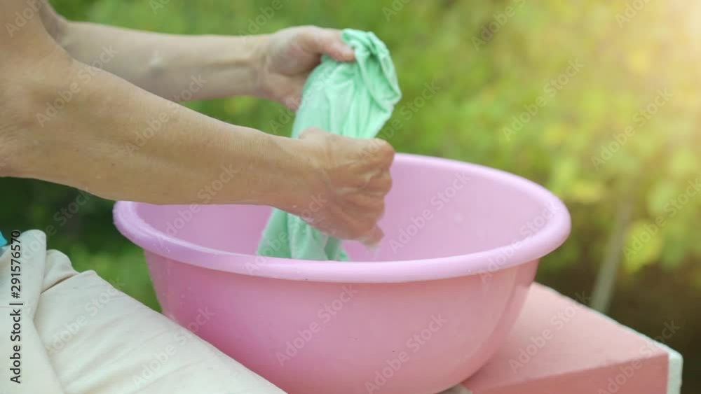 Old woman hands washing clothes in a pink plastic basin Old woman hands washing clothes in a pink plastic basin