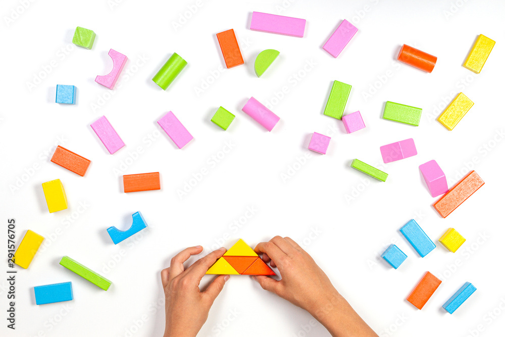 Kid hands playing with colorful wooden building blocks on white table background. Top view Kid hands playing with colorful wooden building blocks on white table background. Top view