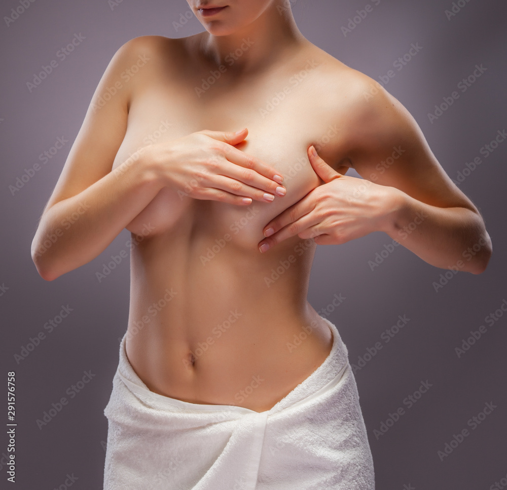 Woman examining her breast on gray background Woman examining her breast on gray background