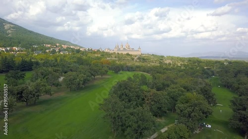golf course in a forest of ash with the historic monastery of escorial crowning a hill, aerial view  photo