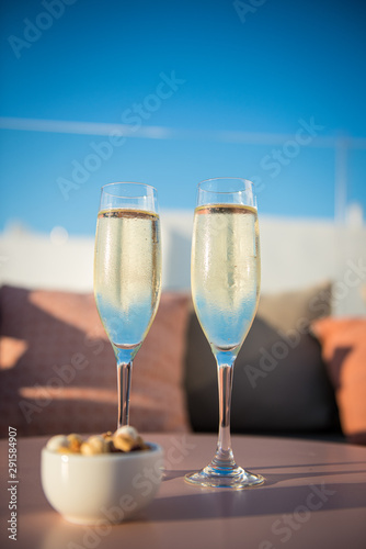 Two glasses of champagne on a terrace with peanuts for apero