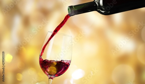 Pouring red wine in a glass isolated on white background