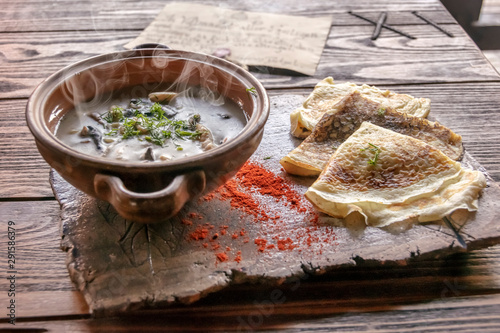 А triangle pankcakes with chicken and mushrooms in sauce close-up on a stone tablet on a table . Horizontal. selective focus. photo