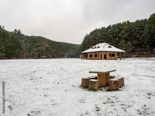 Winter mountain landscape with wooden shelter, trees and snow-covered paths. Birth of the Arlanza river, Sanza, in the town Quintanar de la Sierra photo