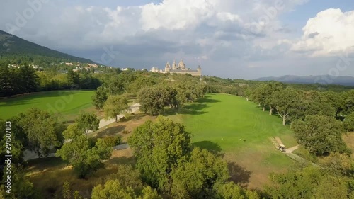 golf course in a forest of ash with the historic monastery of escorial crowning a hill, aerial view over a golf fairway photo