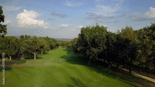 golf course in a forest of ash with the historic monastery of escorial crowning a hill, aerial view over hills photo