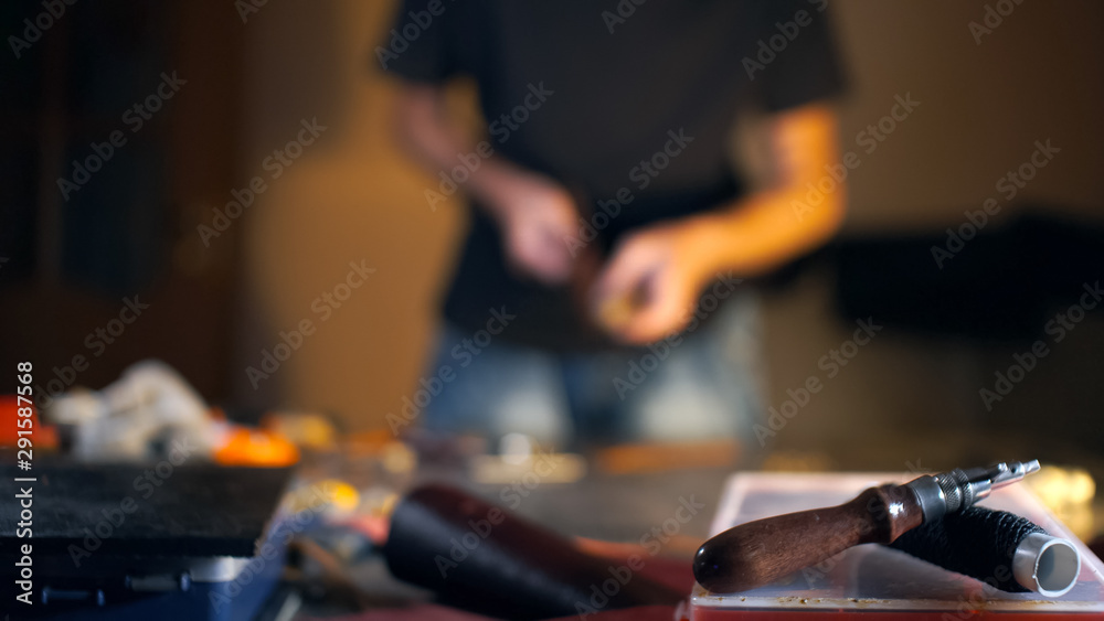 Tanner tools in soft focus. Blurred background with man in authentic workshop.