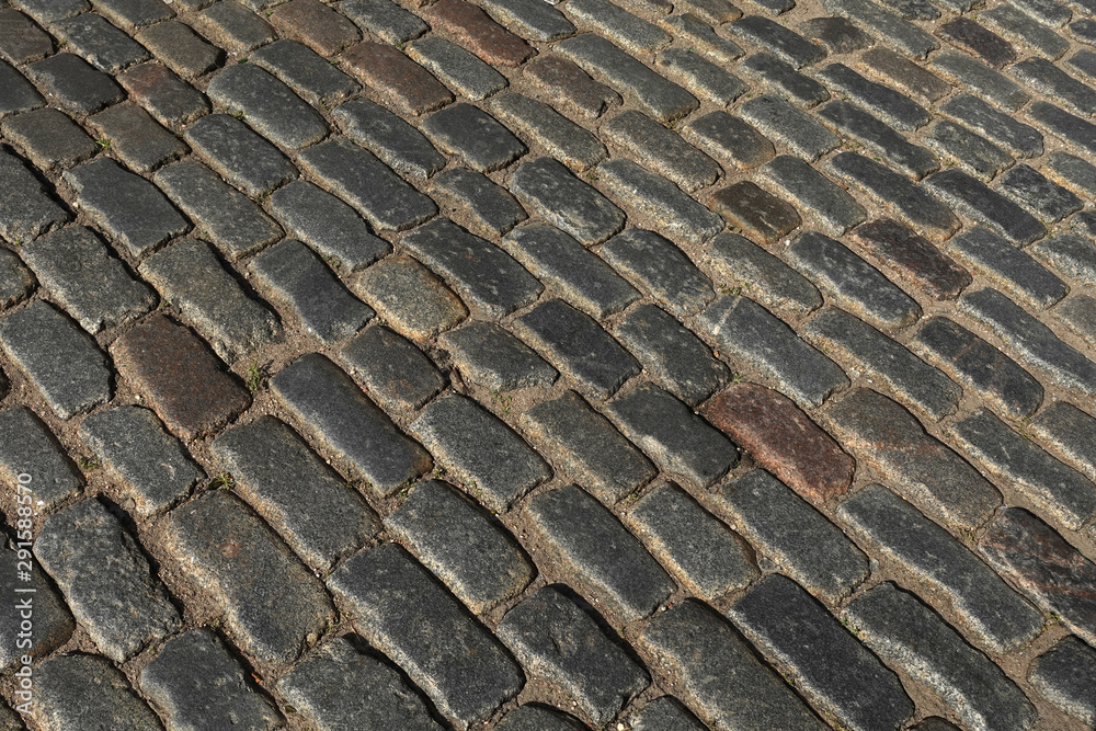 Old old dark paving cobblestone outdoors as background diagonal view close up Old old dark paving cobblestone outdoors as background diagonal view close up