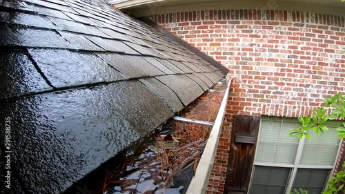 Clogged gutter full of water during rain storm photo