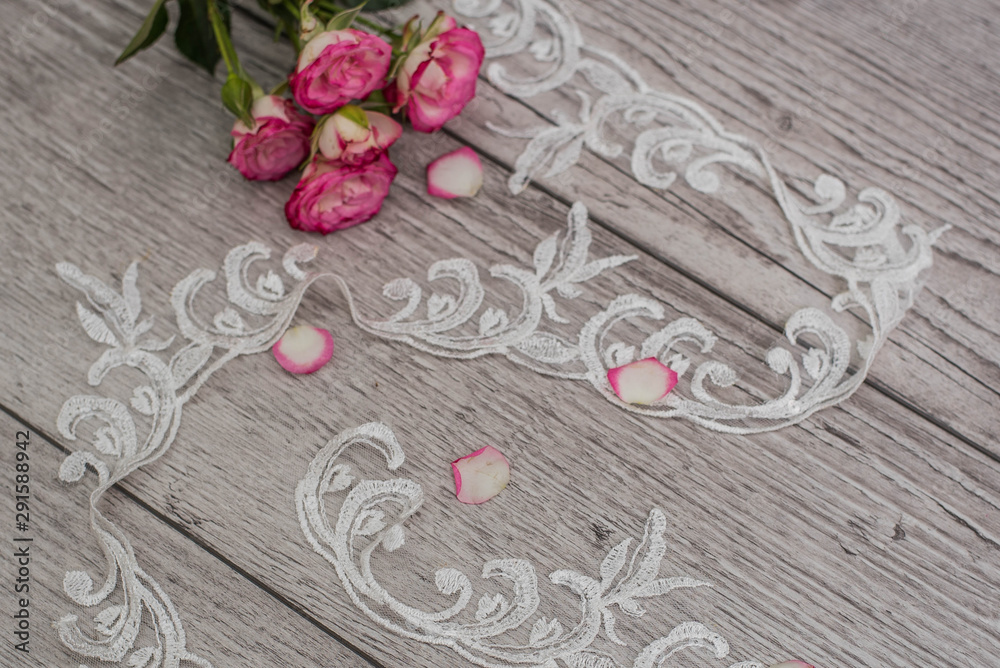 White wooden background with white spring flowers roses and lace ribbon. Happy womans day. The texture of lace on wooden background. White wooden background with white spring flowers roses and lace ribbon. Happy womans day. The texture of lace on wooden background.