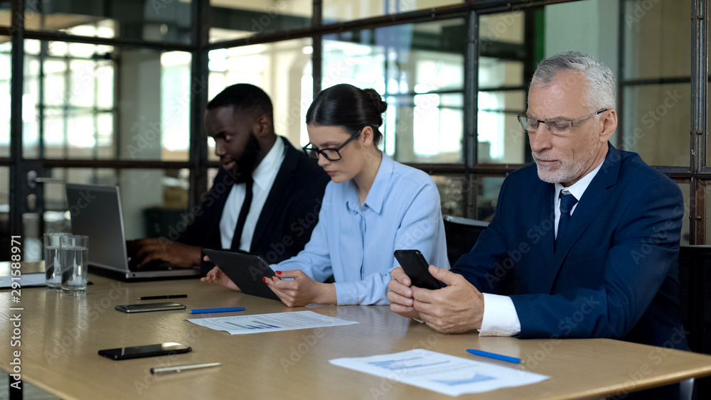 Multiracial group of office employees working smartphone, tablet and laptop