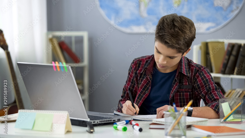 School pupil writing notebook doing home work at table, distance education School pupil writing notebook doing home work at table, distance education
