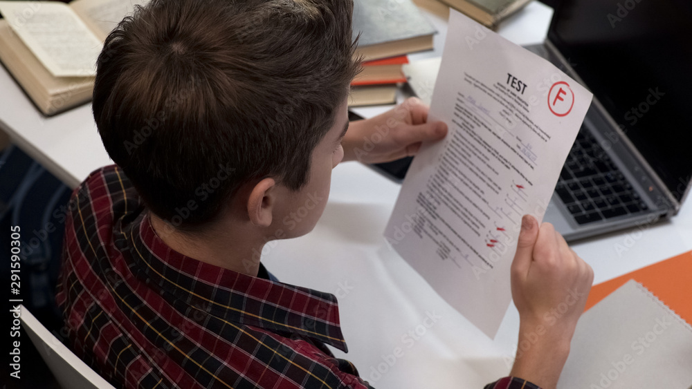 Fototapeta premium Child reading test result holding paper sheet with negative mark, school system