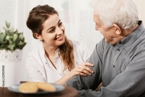 Wallpaper Mural Smiling young nurse sitting at table with senior patient Torontodigital.ca