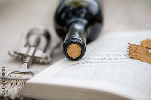 a bottle of wine and an opener in an open book