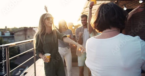 Happy bearded hippie male joining cheerful friends on roof terrace party, chillout