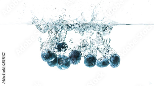 Fresh blueberries falling in water on white background. Fruits splashing into clear water.