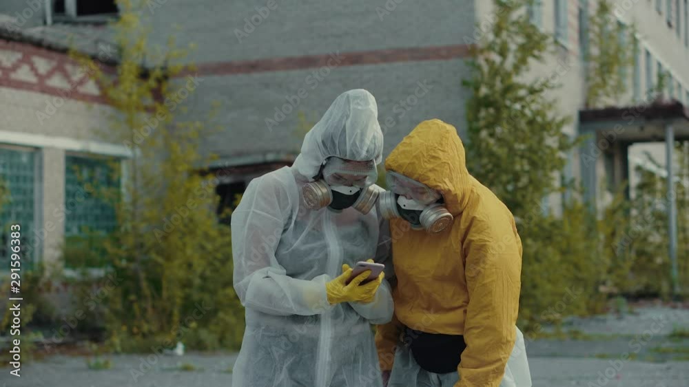 Scientists put on respirators and take pictures on the phone. Girls in a protective suit from radiation take selfies. Ecological theme. Terrible abandoned territory in Novosibirsk. Scientists put on respirators and take pictures on the phone. Girls in a protective suit from radiation take selfies. Ecological theme. Terrible abandoned territory in Novosibirsk.