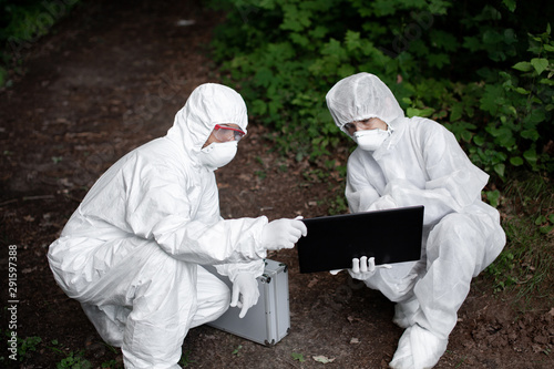 Ecological problem. Pollution. Examine soil. Scientist working in forest in protective mask and suit taking water and soil samples. Chemist makes an analysis of the environment for radiation. 