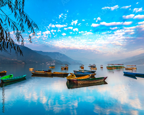 Sunrise in Phewa Lake with Multicolor boats.blue sky reflection in the lake.