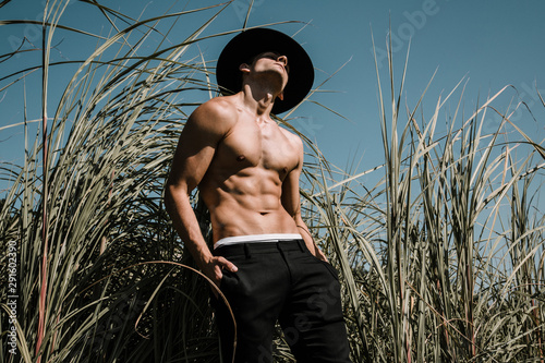 Portrait of a handsome shirtless young man in a black hat. Fashion country concept. Outdoor shot.