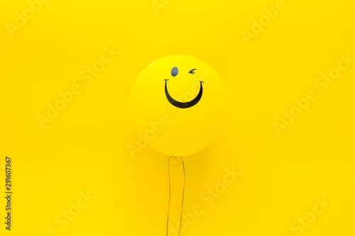 Happiness emotion. Yellow balloon with smile on yellow background top view copy space