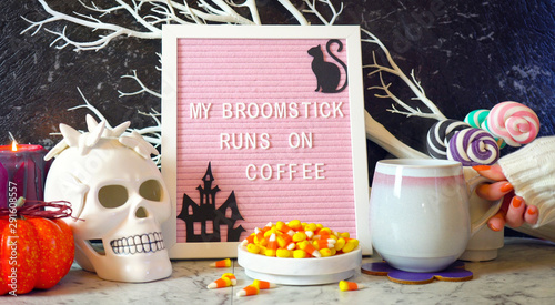 Funny Halloween mantel table set up with My Broomstick Runs on Coffee letter board with woman's hand drinking coffee.