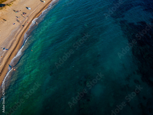 Aerial view of a beach with umbrellas and bathers at sunset. Seabed. Beach of Buljarica one of the largest beaches at the coast of Montenegro, close to Petrovac in direction of Bar. Budva municipality