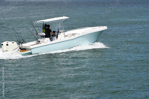 Light blue with white trim open sport fishing boat powered by two outboard engines