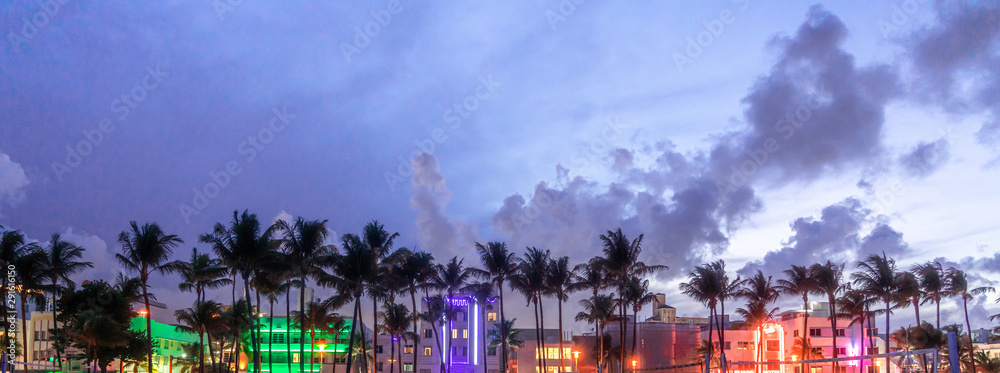 Fototapeta Panorama Miami Drive Ocean Drive z hotelami i restauracjami o zachodzie słońca. Panoramę miasta z palmami w nocy. Życie nocne w stylu art deco na południowej plaży