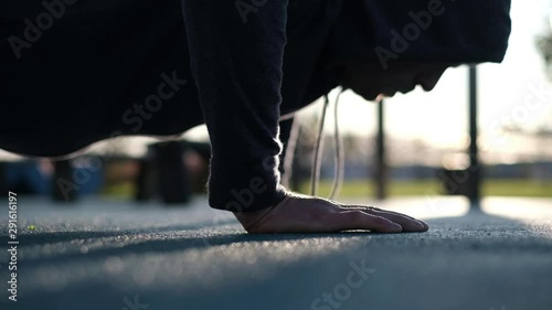 A man doing a push up slowly in a park on cold weather breathing deeply. Close up view. He has steam coming out of his mouth
