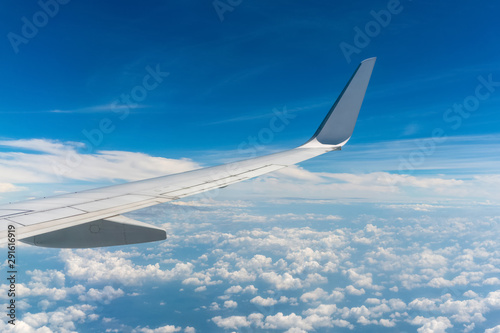 an airplane wing over the cloudy blue sky