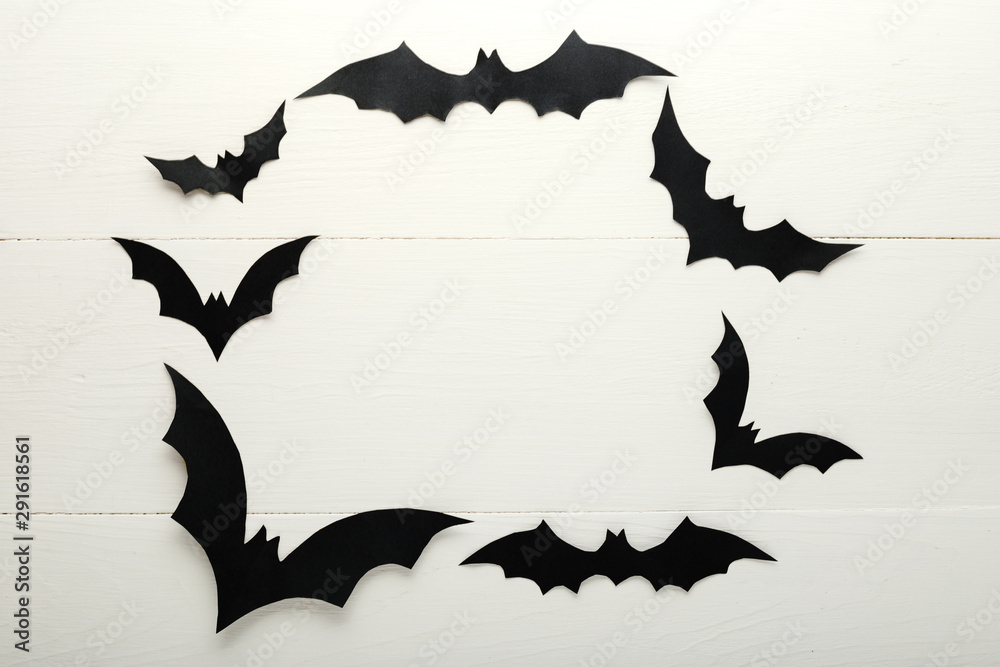 Naklejka premium Halloween background with paper bats on white wooden background. Frame. Halloween holiday decorations. Flat lay, top view, copy space. Party invitation mockup, celebration.