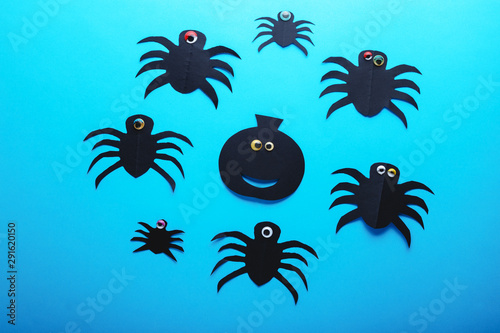 Funny paper spiders and pumpkin with eyes on a blue background. Halloween decorations concept. Happy Halloween day. Flat lay  top view. Party invitation  celebration.