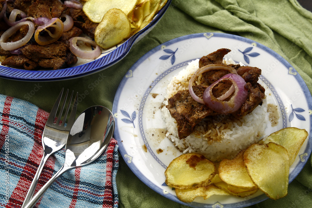 Bistek Tagalog or fried pork tenderloin in soy sauce with potato chips