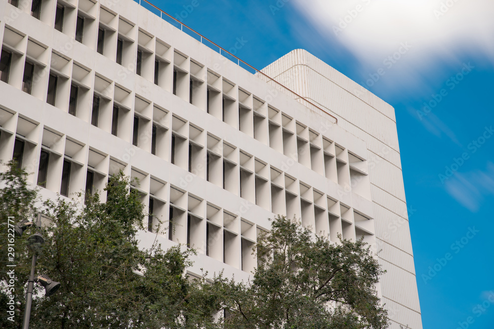 Fototapeta premium Generic office building structure on a blue sky with trees in foreground