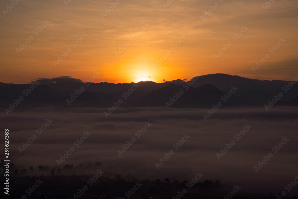 Sunrise on the mountain with mist on top valley in colourful background sky